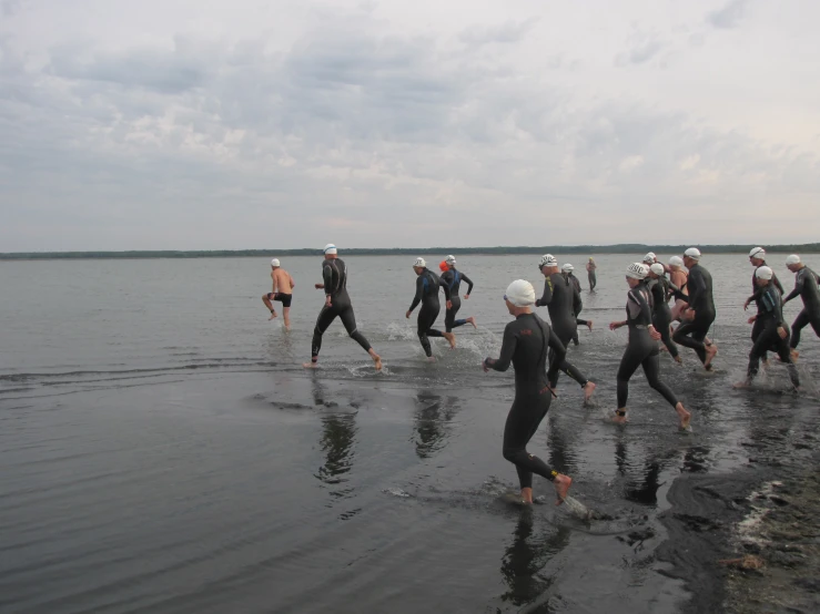 people are wading in shallow waters with wet suits