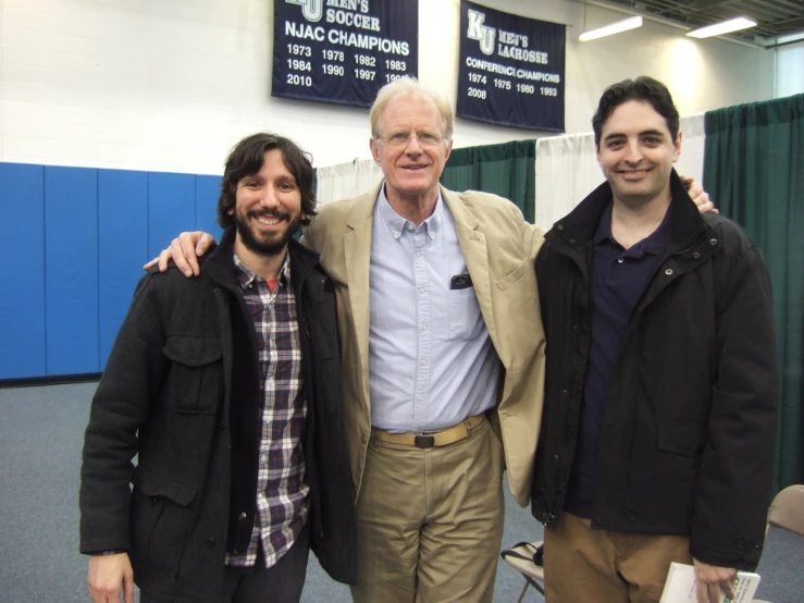 three men standing next to each other posing for the camera