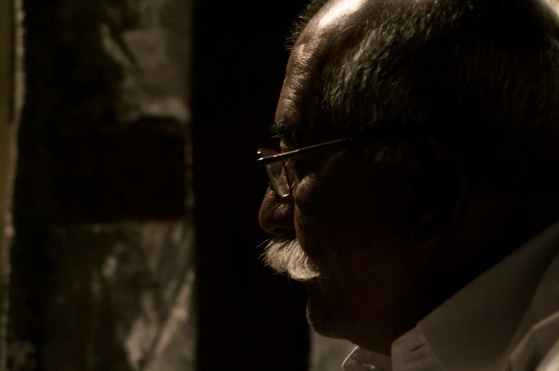 a close - up of the head and shoulders of an elderly man wearing glasses