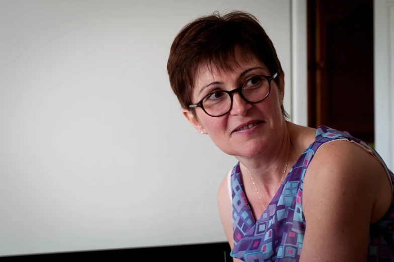 a woman wearing glasses while leaning on a laptop