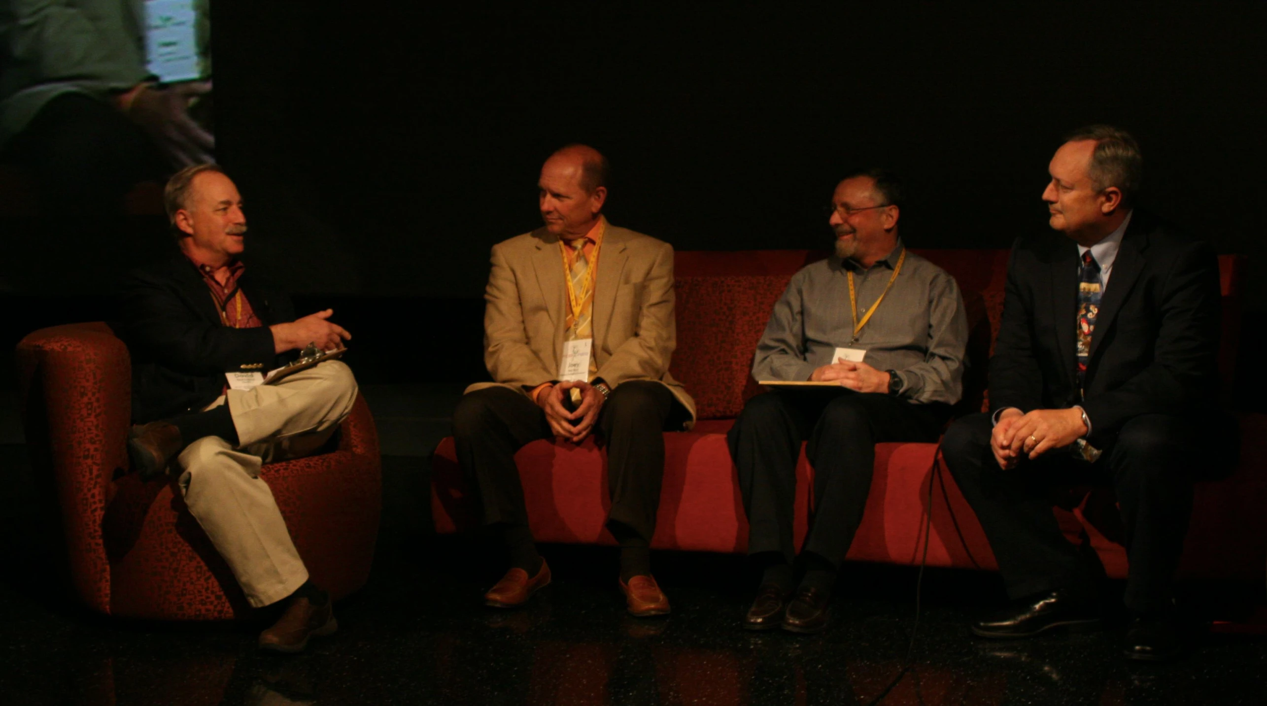 a group of three men sitting on top of a red couch