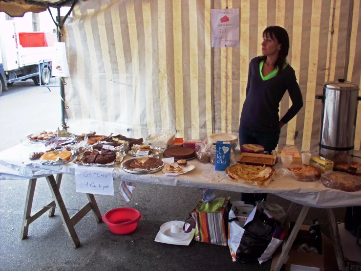 a woman stands behind a table with a lot of food on it