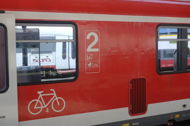 the side of a red passenger train with a bicycle on it