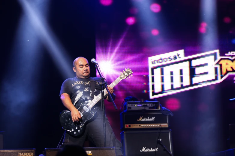 a man on stage with his guitar and headphones on