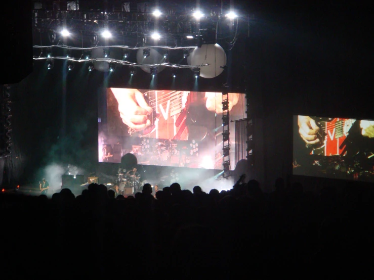 concert lights illuminate an open stage as the crowd watches