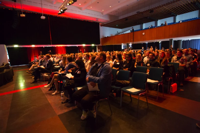 a group of people sit and listen to someone on stage