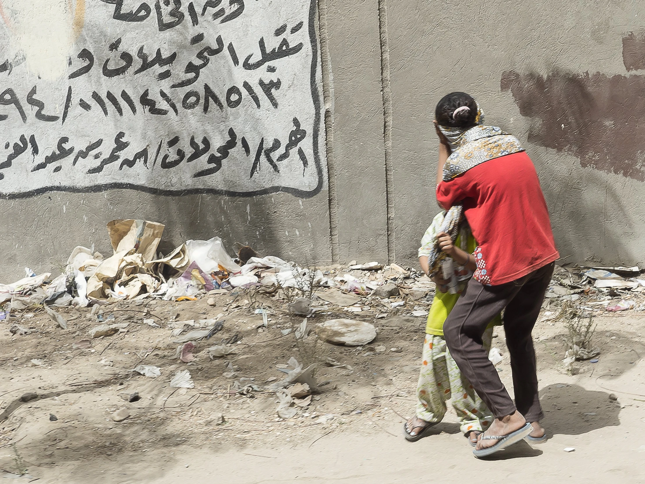 a man and woman walking past some trash on a street