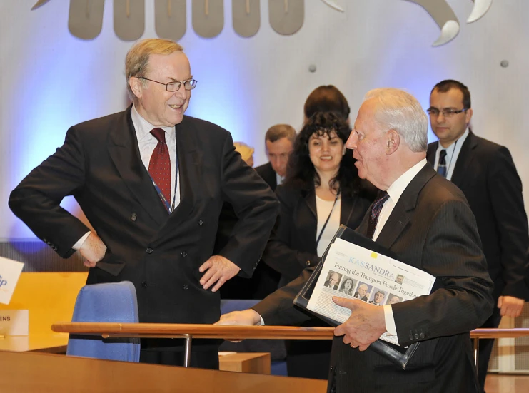 two men shake hands as other people look on