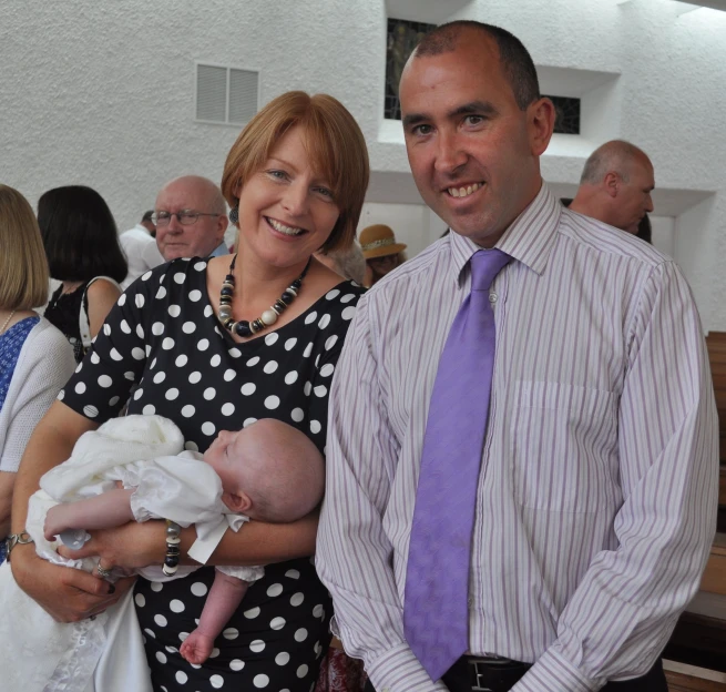 a couple smiling with baby dressed in polka dots