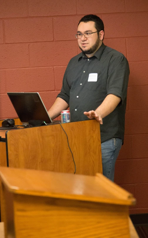 a man standing next to a laptop computer at a podium