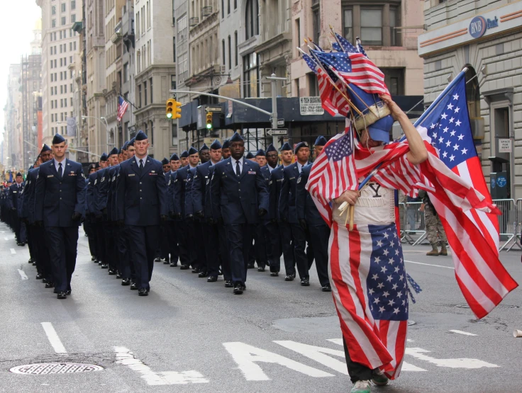 the people are carrying american flags as they march in a parade