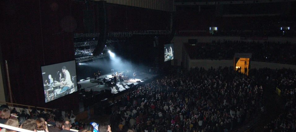 an empty concert hall at night with a massive screen and crowd