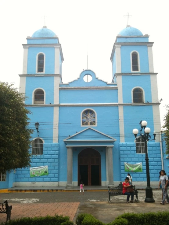 a blue building is painted light blue with two towers and three windows
