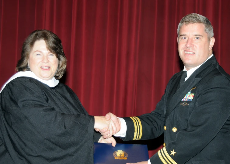 two men shaking hands and standing in front of a curtain