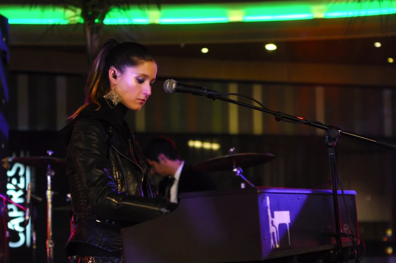 a woman standing in front of a microphone and playing an instrument