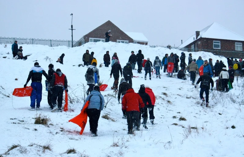 a bunch of people walking through a snow covered area