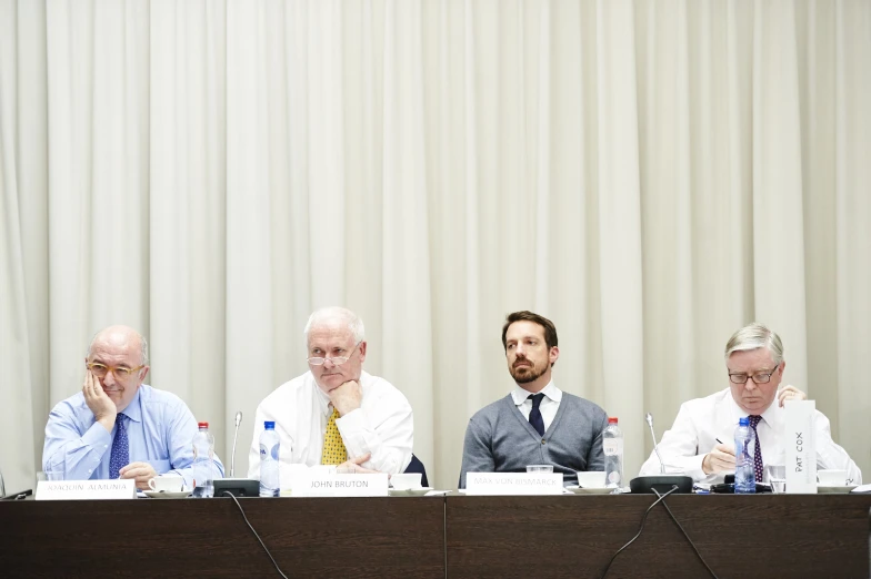 four men sitting down at a table having a discussion