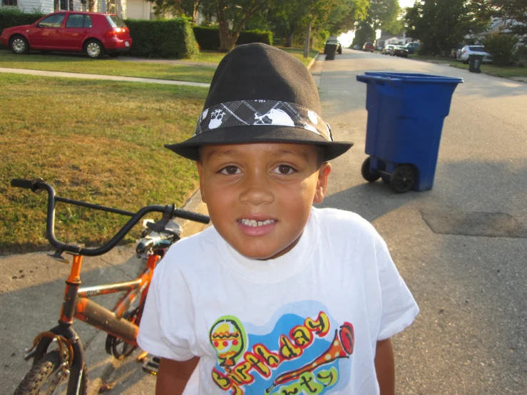 a boy wearing a hat near a bicycle