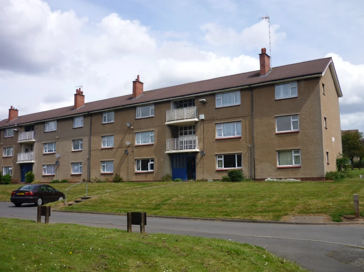 a view of an apartment building with lawn, grass, and driveway