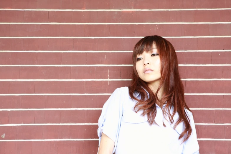 a woman standing against a red brick wall