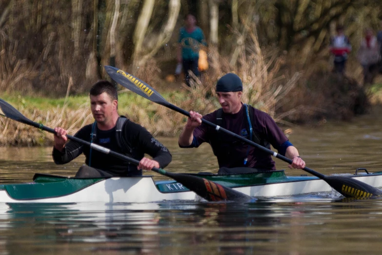 two men paddle in their canoes on the river