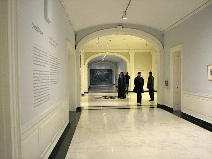the three men are walking down the long hallway