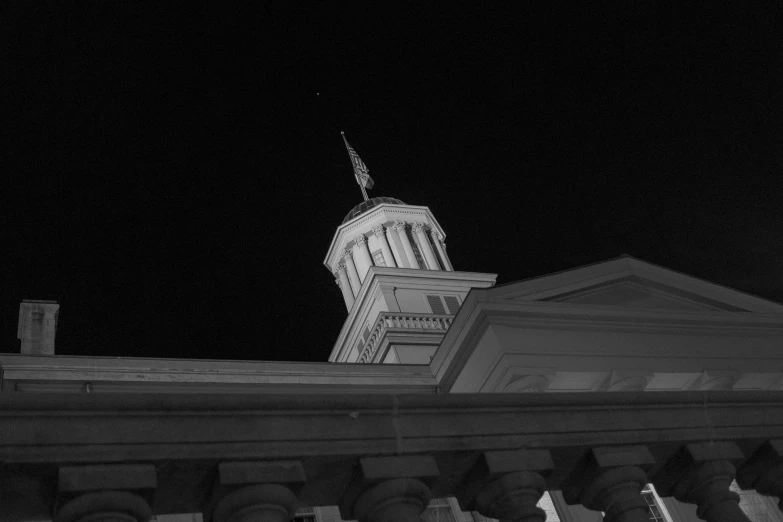 the view from a building at night showing a steeple and flag