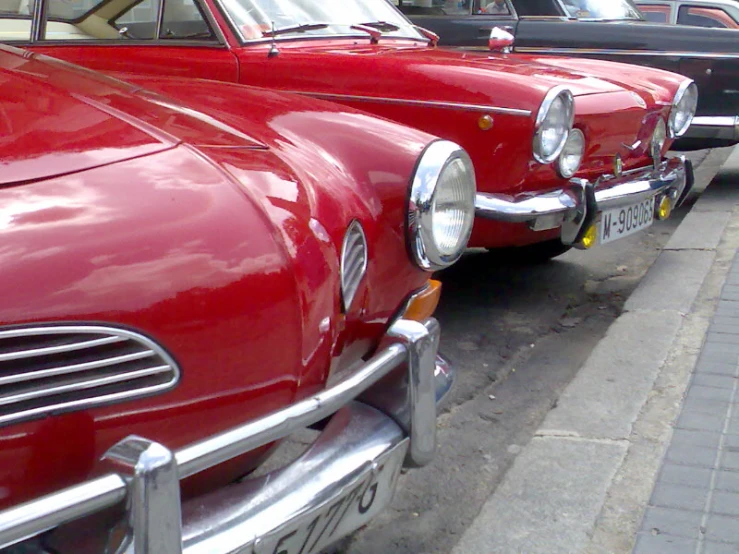 a row of old school red cars lined up on the curb