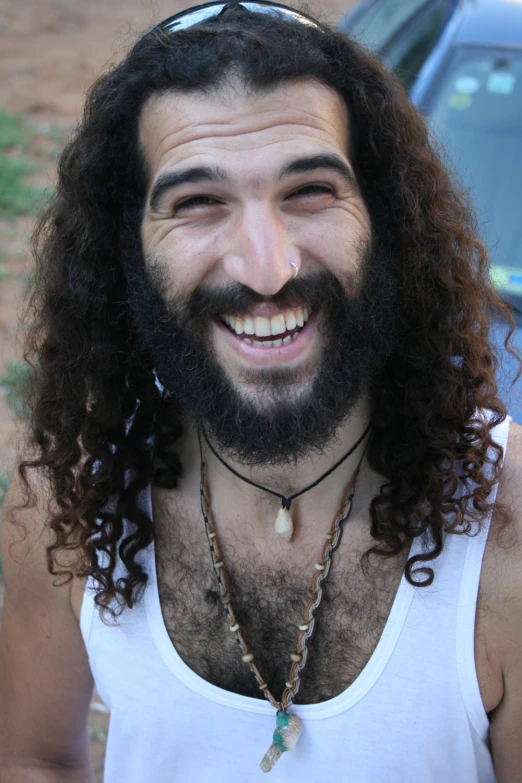 a man with long curly hair wearing glasses smiling