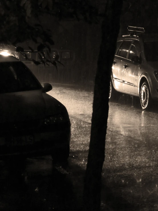 a dark car is parked on a rainy night