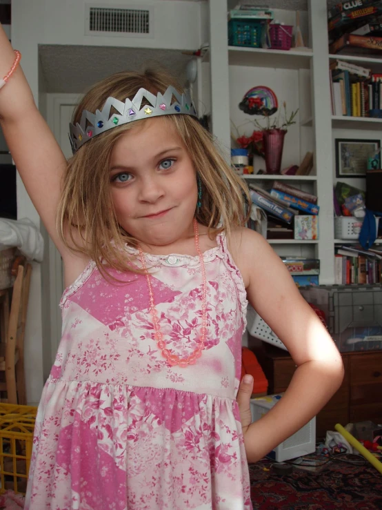 a  wearing a tiara stands in her living room