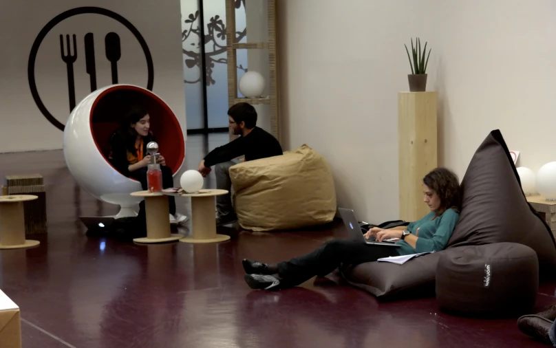 a man and woman sitting on bean bag chairs looking at their laptop