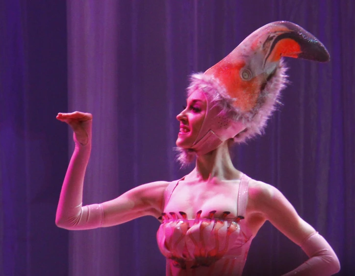 a woman dressed up as a flamingo, standing with her arm out