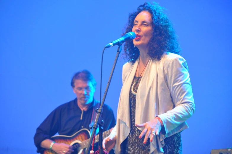 woman in dress standing next to man with guitar on stage