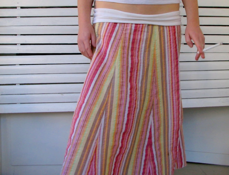 a woman wearing a striped skirt while holding onto her hand