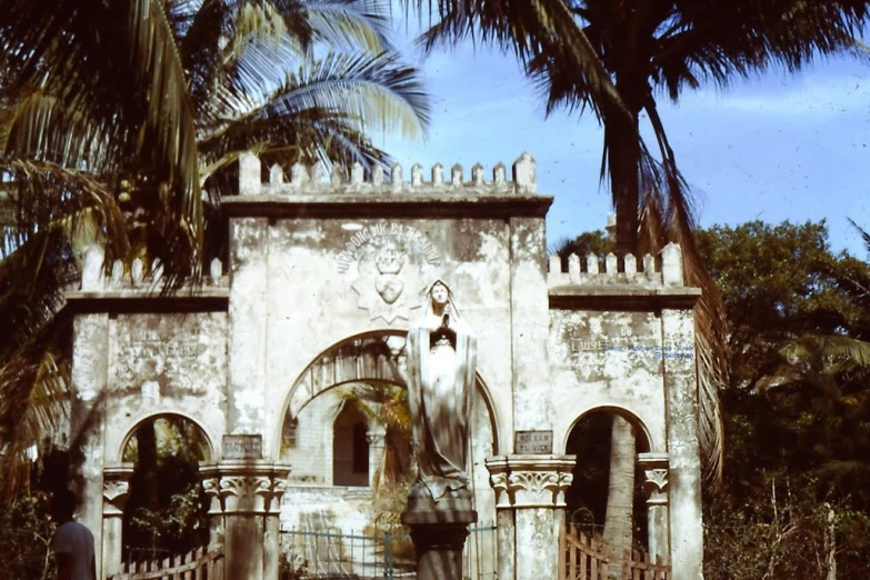 a large gate and some palm trees with a building in the background