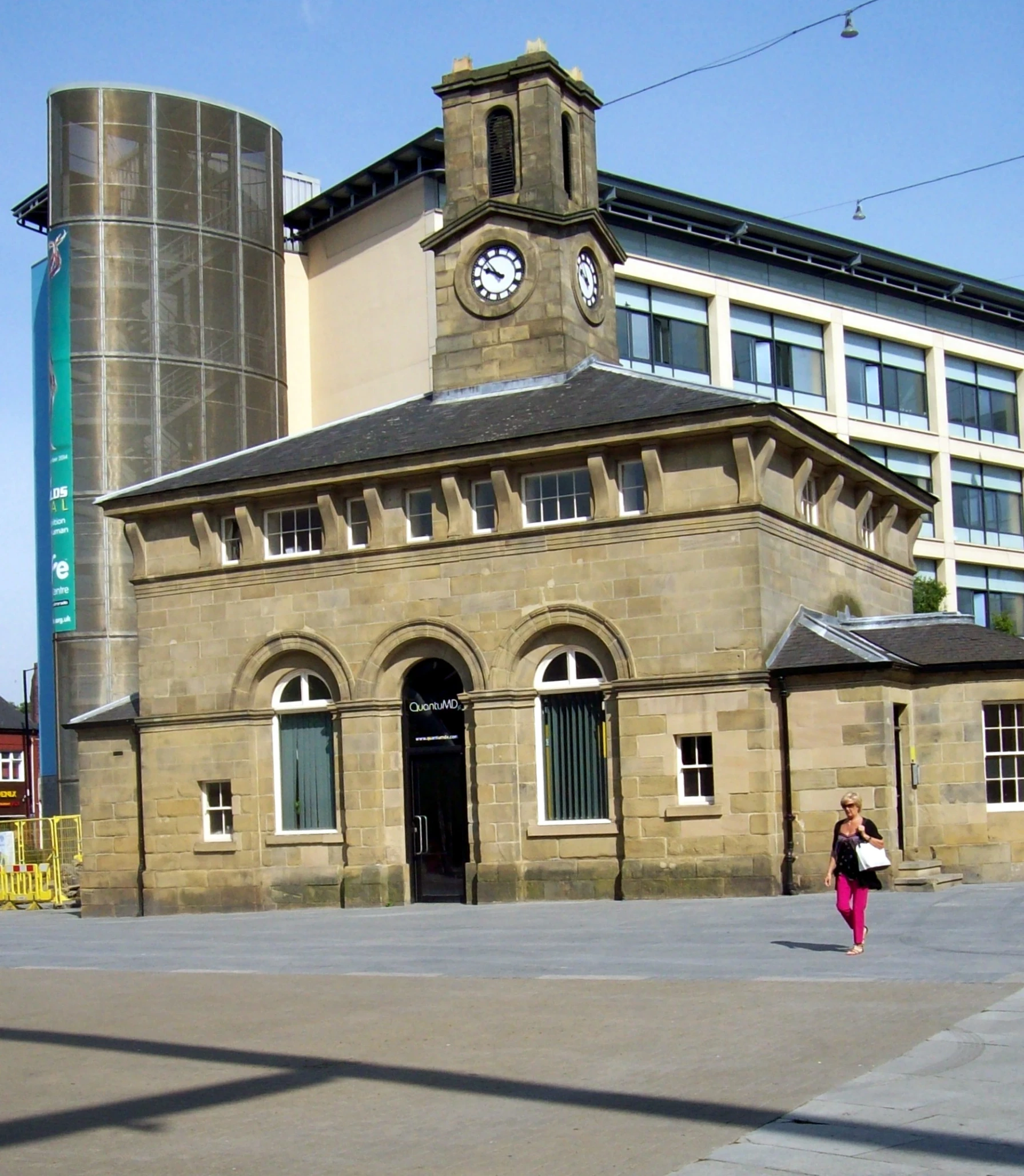 the clock tower stands tall above the small building