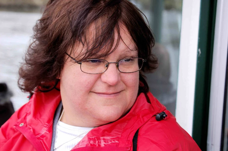 a woman with dark hair and glasses looking off into the distance