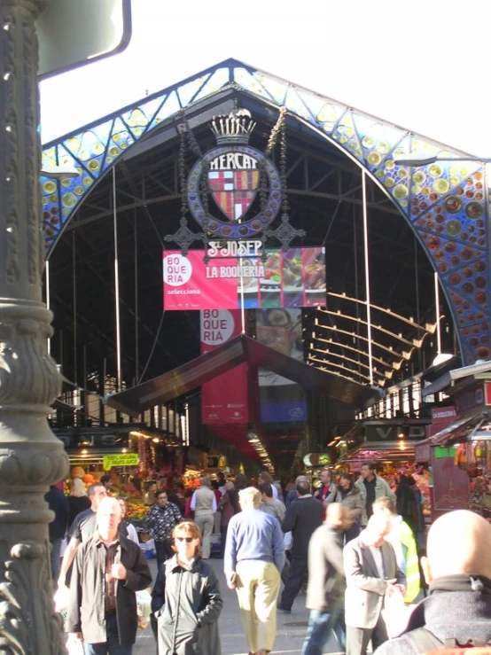 a group of people walking down a street near a large gate