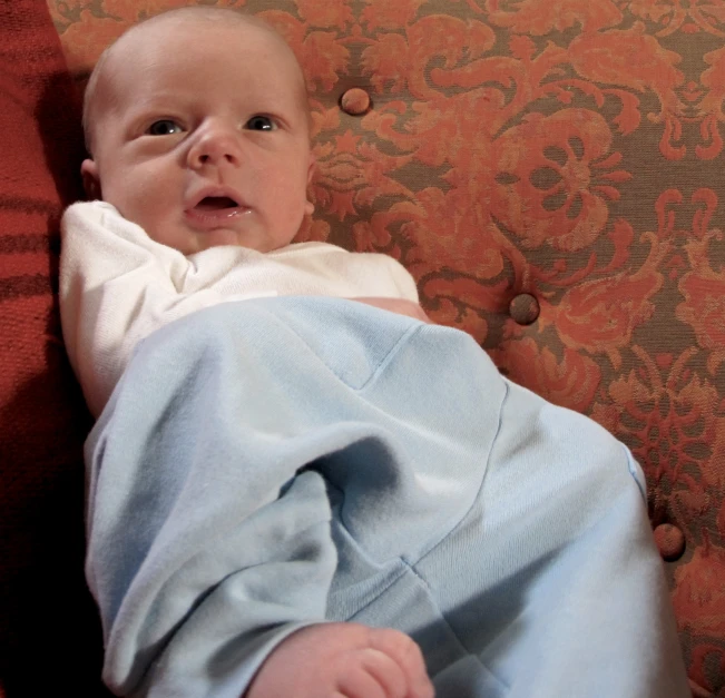 a baby in pajamas is lying down on a chair