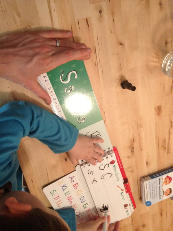 people are writing with their fingers on paper and on a wooden surface