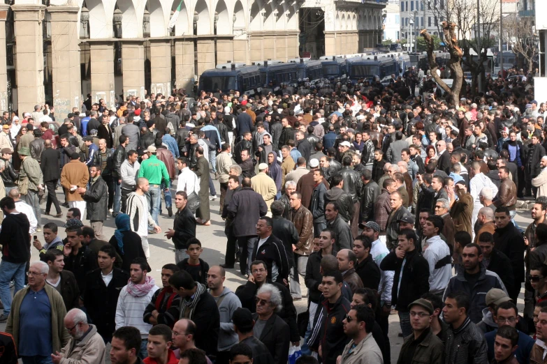 a large crowd of people walk around a busy city street