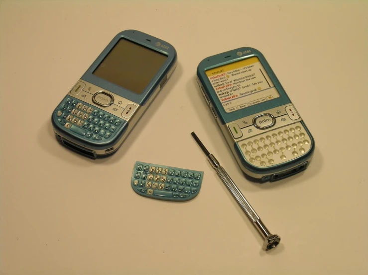 a white table with three cell phones and a stick