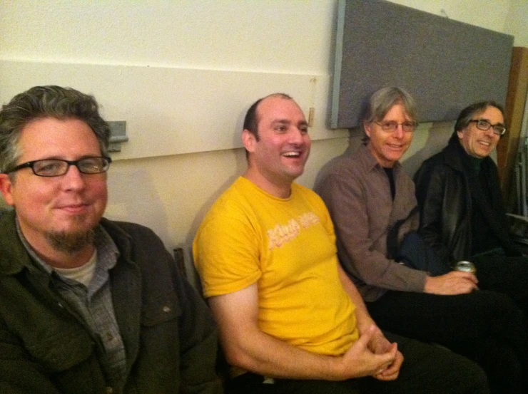 four guys in a group smile and sit in front of the camera