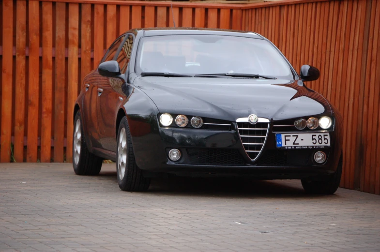 a black car parked in front of a brown fence