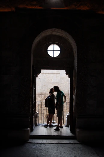 two people standing in an archway holding hands