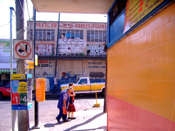 two people are walking down a sidewalk