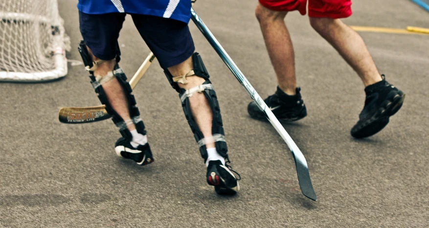 two people are walking in opposite directions holding hockey sticks