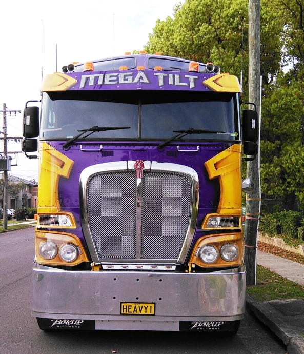 a large purple and yellow truck parked next to a traffic light