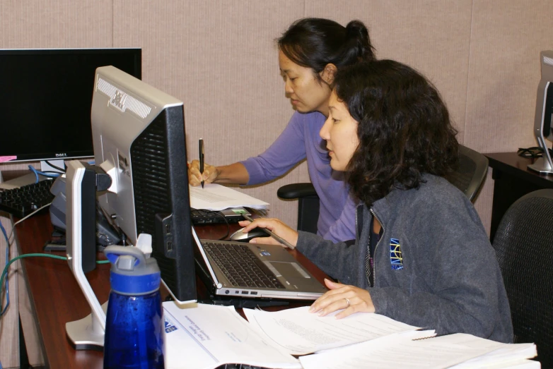 two women at a desk with a laptop computer